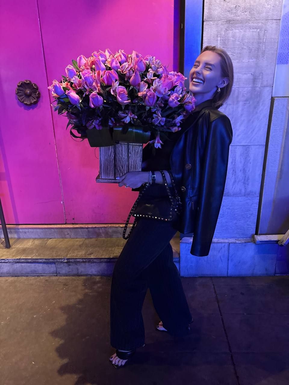 Daria Nesterova smiling, holding a big bouquet of pink roses